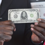Sheldon Greenland displays the $1,000 bill donation at Hobby Lobby on Saturday.